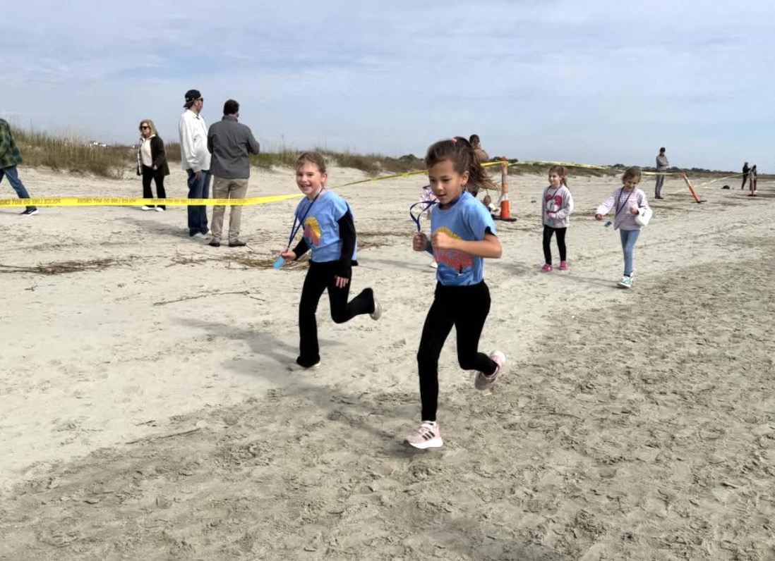 Students run along the sand during the Soar on Skimmers Fun Run