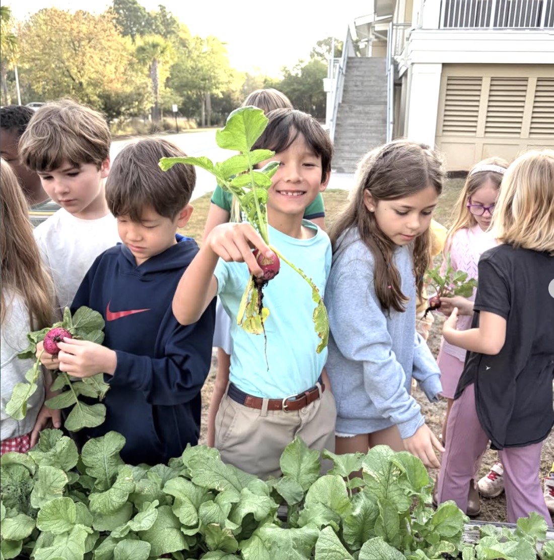 Students proudly show radishes they harvested from the Green Heart garden beds